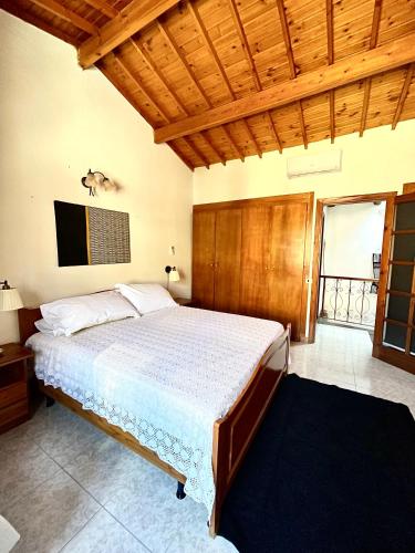 Un dormitorio con una cama grande con techo de madera. en Casa Veronica - accogliente casa su due piani nel cuore del borgo, en Làconi