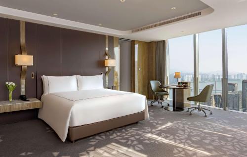 a bedroom with a large white bed and a desk at Conrad Hangzhou in Hangzhou