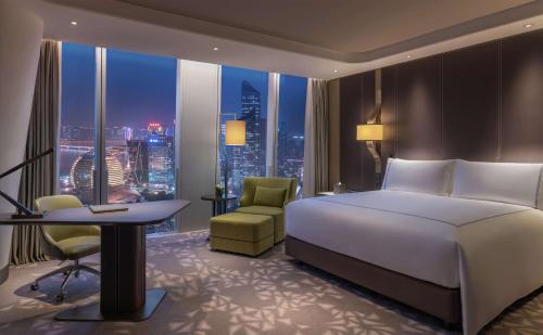 a hotel room with a bed and a desk and a window at Conrad Hangzhou in Hangzhou