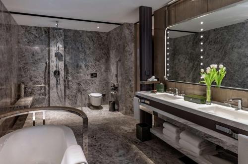 a bathroom with a tub and a sink and a mirror at Conrad Hangzhou in Hangzhou