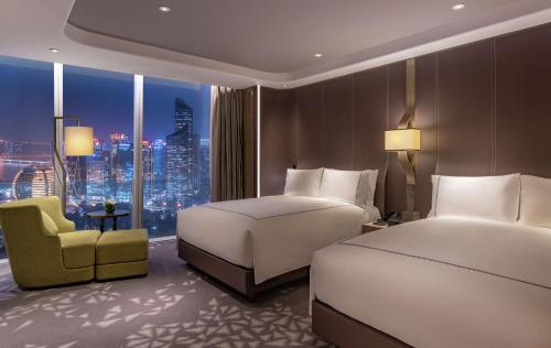 a hotel room with two beds and a chair at Conrad Hangzhou in Hangzhou
