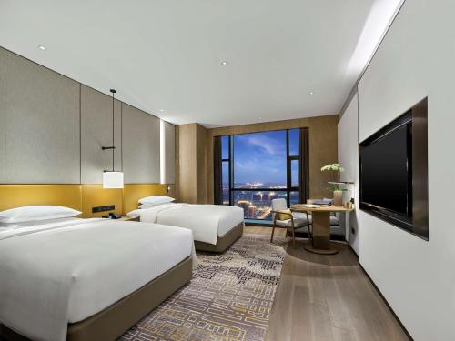 a hotel room with two beds and a television at Hilton Jiaxing in Jiaxing