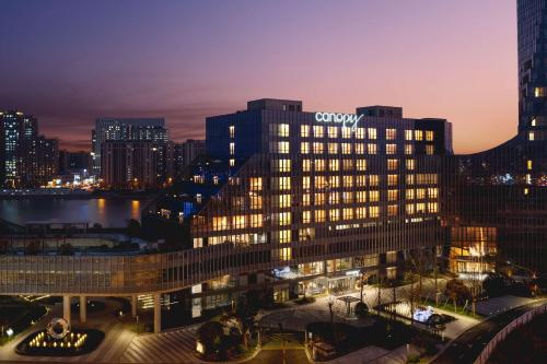 a large building with a sign on top of it at night at Canopy By Hilton Hangzhou Jinsha Lake in Hangzhou