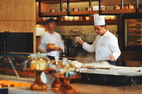 two chefs are preparing food in a kitchen at Canopy By Hilton Hangzhou Jinsha Lake in Hangzhou