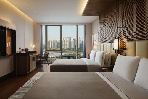 Canopy By Hilton Hangzhou Jinsha Lake في هانغتشو: غرفة فندقية بسريرين ونافذة كبيرة