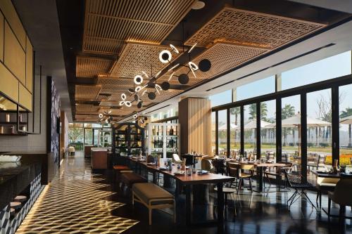 a restaurant with tables and chairs and windows at Canopy By Hilton Hangzhou Jinsha Lake in Hangzhou