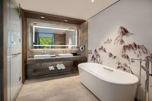 a bathroom with a tub and two sinks and a mirror at Hilton Garden Inn Jiuzhaigou in Jiuzhaigou