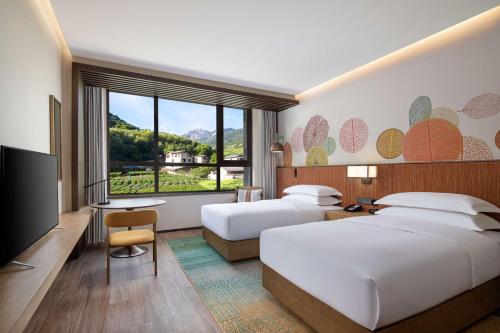 a hotel room with two beds and a flat screen tv at Hilton Garden Inn Jiuzhaigou in Jiuzhaigou