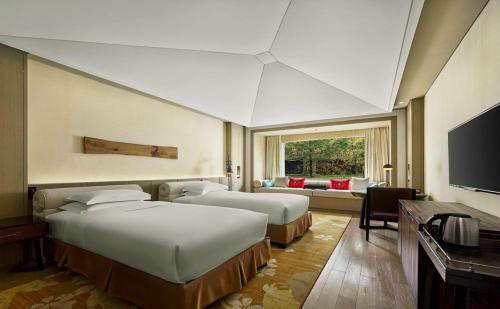 a hotel room with two beds and a television at Hilton Jiuzhaigou Resort in Jiuzhaigou