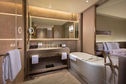 a bathroom with a tub and a large mirror at Hilton Jiuzhaigou Resort in Jiuzhaigou