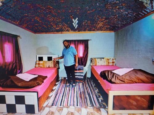 a man standing in a room with two beds at Fox Camp (Moses Lodge) in Saint Catherine