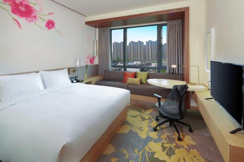 ein Hotelzimmer mit einem Bett, einem Schreibtisch und einem TV in der Unterkunft Hilton Garden Inn Qidong in Qidong