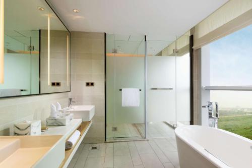 y baño con bañera, lavamanos y ducha. en Hilton Garden Inn Zhuhai Hengqin en Zhuhai