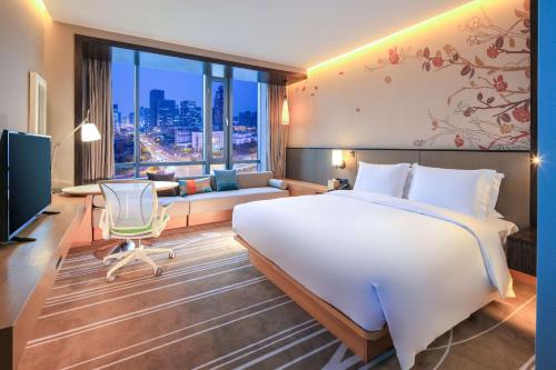 a bedroom with a large bed and a living room at Hilton Garden Inn Ningbo in Ningbo