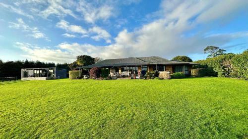 a house with a large green field in front of it at Heaven's Rest B&B in Pukekohe East