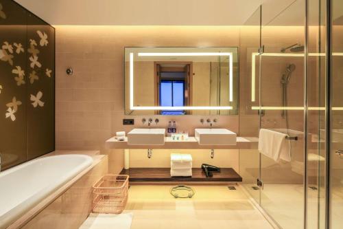 a bathroom with two sinks and a tub and a mirror at Hilton Garden Inn Ningbo in Ningbo