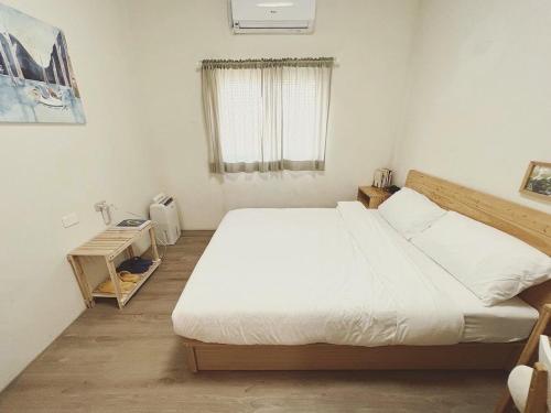 a bedroom with a large white bed and a window at 微光書旅-輕旅 in Tongluo