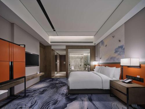 a hotel room with a bed and a television at Hilton Guiyang in Guiyang