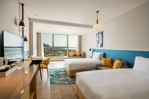 a hotel room with two beds and a tv at Hilton Garden Inn Zhuhai Hengqin Sumlodol Park in Zhuhai