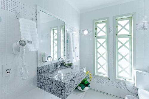 bagno bianco con lavandino e specchio di Bristol Sabrina Hotel de Charme Joinville a Joinville