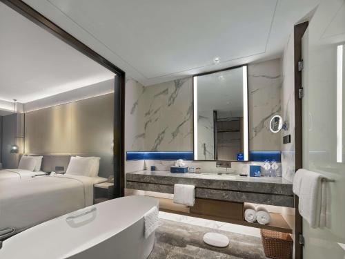 a bathroom with a bed and a bath tub and a sink at DoubleTree by Hilton Qidong in Qidong
