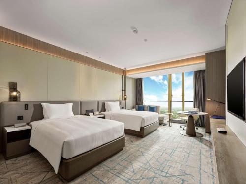 a hotel room with two beds and a television at DoubleTree by Hilton Qidong in Qidong