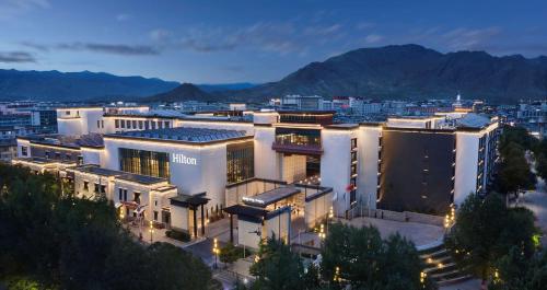 a large white building with a city at night at Hilton Shigatse in Shigatse