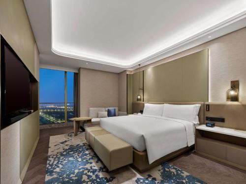 a bedroom with a large bed and a television at DoubleTree by Hilton Qidong in Qidong