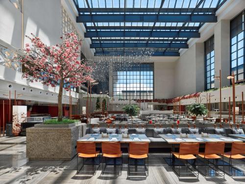 Hilton Shigatse في شيغاتسي: غرفة طعام كبيرة مع طاولات وشجرة