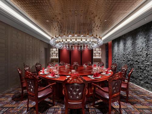 a dining room with a table and chairs and a chandelier at Hilton Shigatse in Shigatse