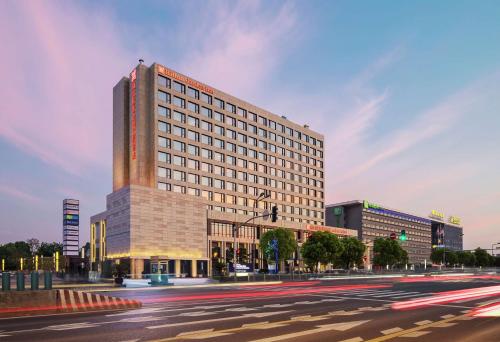 a large building on a city street with a street at Hilton Garden Inn Shanghai Hongqiao NECC in Shanghai