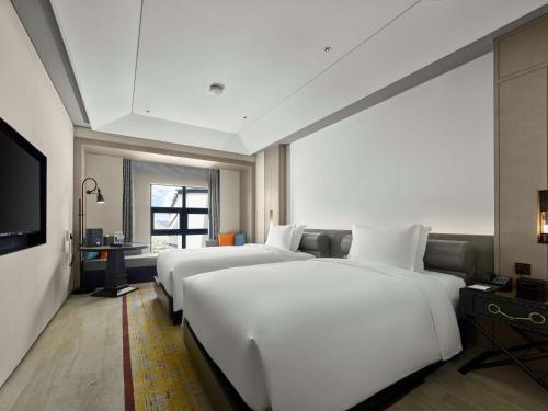 a hotel room with two beds and a television at Hilton Shigatse in Shigatse