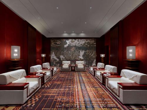 a waiting room with white chairs and a painting on the wall at Hilton Shigatse in Shigatse