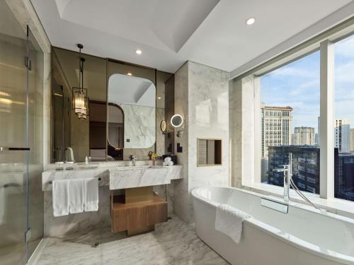 un bagno con due lavandini, una vasca e una finestra di Hilton Shanghai Hongqiao a Shanghai