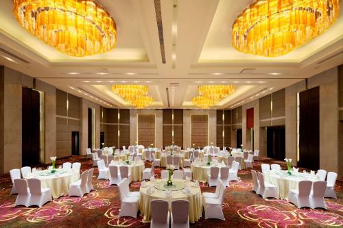 une salle de banquet avec des tables blanches, des chaises et des lustres dans l'établissement DoubleTree by Hilton Shenyang, à Shenyang