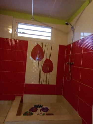 un bagno rosso con doccia e piastrelle rosse di Maison LAVANNE a Saint-Joseph
