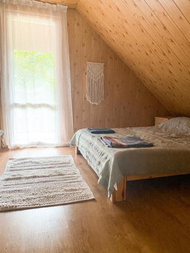 a bedroom with a bed and a large window at Chata przy lesie in Łuka
