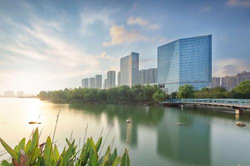Hilton Suzhou Yinshan Lake في سوتشو: اطلاله على نهر في مدينه بها مباني