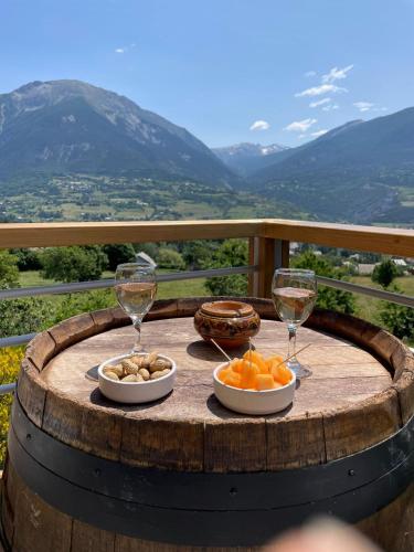 a table with wine glasses and fruit on a barrel at Gîte confort 15 couchages, vue panoramique Montagne Hautes Alpes, Terrasses in Embrun