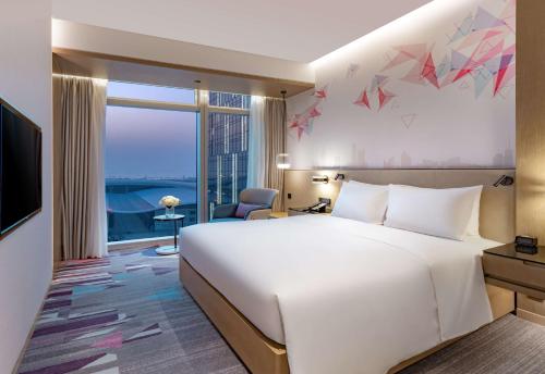 a hotel room with a large white bed and a window at Hilton Garden Inn Shenzhen World Exhibition & Convention Center in Shenzhen