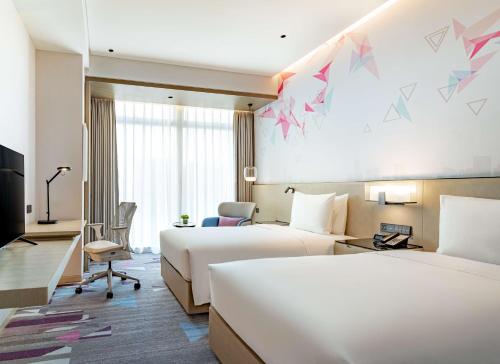 a hotel room with two beds and a desk at Hilton Garden Inn Shenzhen World Exhibition & Convention Center in Shenzhen