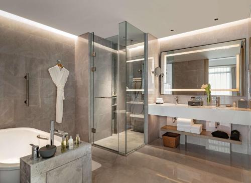 uma casa de banho com um chuveiro, uma banheira e um lavatório. em Hilton Garden Inn Shenzhen World Exhibition & Convention Center em Shenzhen