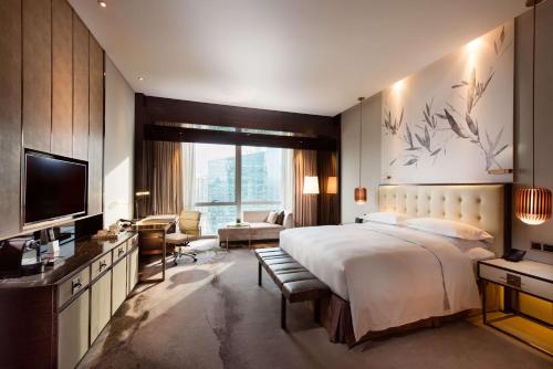 a bedroom with a large bed and a television at Hilton Shenzhen Futian, Metro Station at Hotel Front Door, Close to Futian Convention & Exhibition Center in Shenzhen