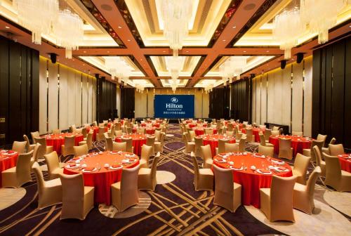 a large room with tables and chairs and a stage at Hilton Shenzhen Futian, Metro Station at Hotel Front Door, Close to Futian Convention & Exhibition Center in Shenzhen