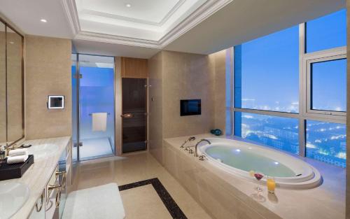 uma casa de banho com banheira e uma grande janela em DoubleTree by Hilton Hotel Qingdao-Jimo Ancient City em Jimo