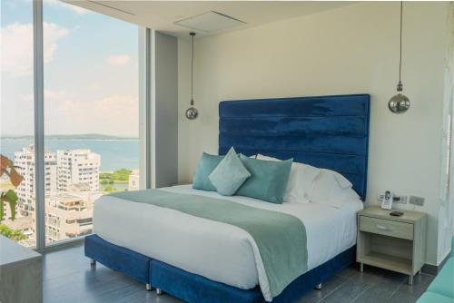 a bedroom with a blue bed with a large window at Hotel Zi One Luxury in Cartagena de Indias