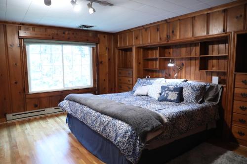 Schlafzimmer mit einem Bett mit Holzwänden und einem Fenster in der Unterkunft Duke Forest Gem! 3br, Sleeps 7 in Durham