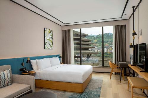ein Hotelzimmer mit einem Bett, einem Schreibtisch und einem Fenster in der Unterkunft Hilton Garden Inn Guizhou Maotai Town in Maotai