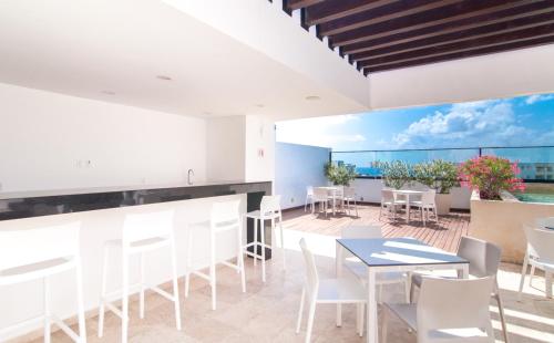 a patio with white chairs and tables and a view of the ocean at Kuxtal 3 Bedroom Downtown Apartment by Casago in Playa del Carmen