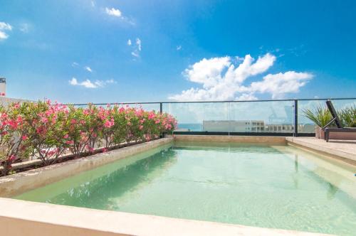 a swimming pool with pink flowers on a balcony at Kuxtal 3 Bedroom Downtown Apartment by Casago in Playa del Carmen